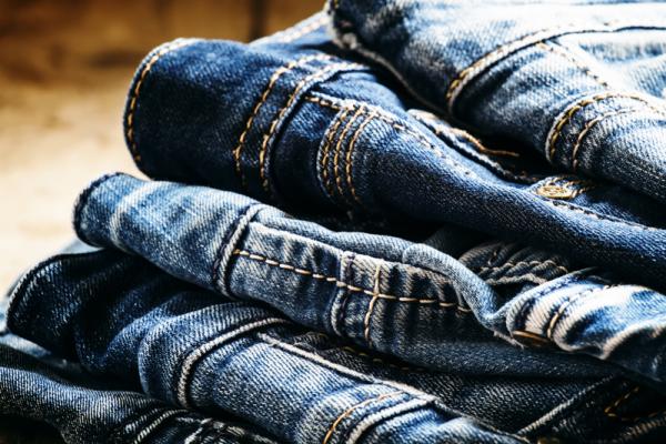 Classic casual blue jeans, pile on a vintage wooden background, selective focus